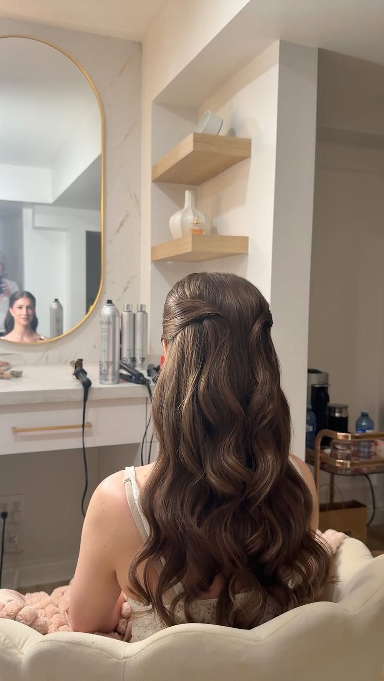 Woman with long brown wavy hair in a half-up half-down wedding hairstyle.