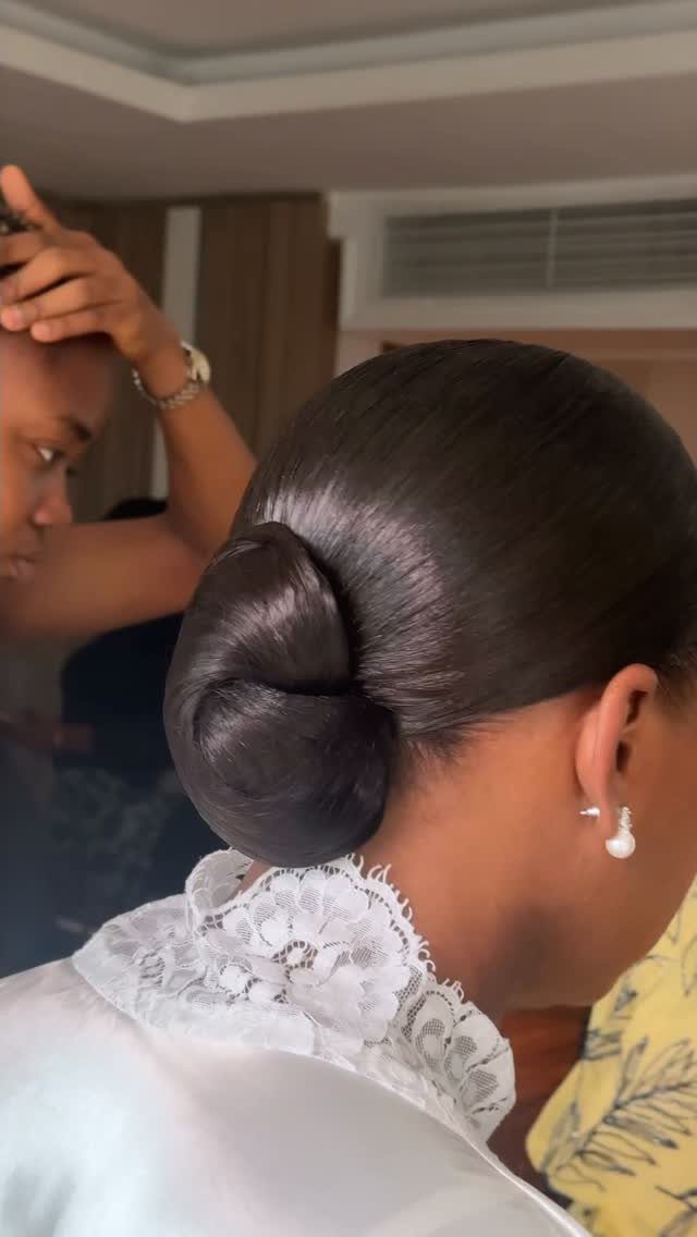 Sleek dark hair styled in a polished low bun with white lace collar.