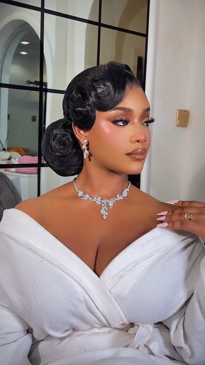 Woman with sculpted finger waves and a low bun wearing bridal jewelry.