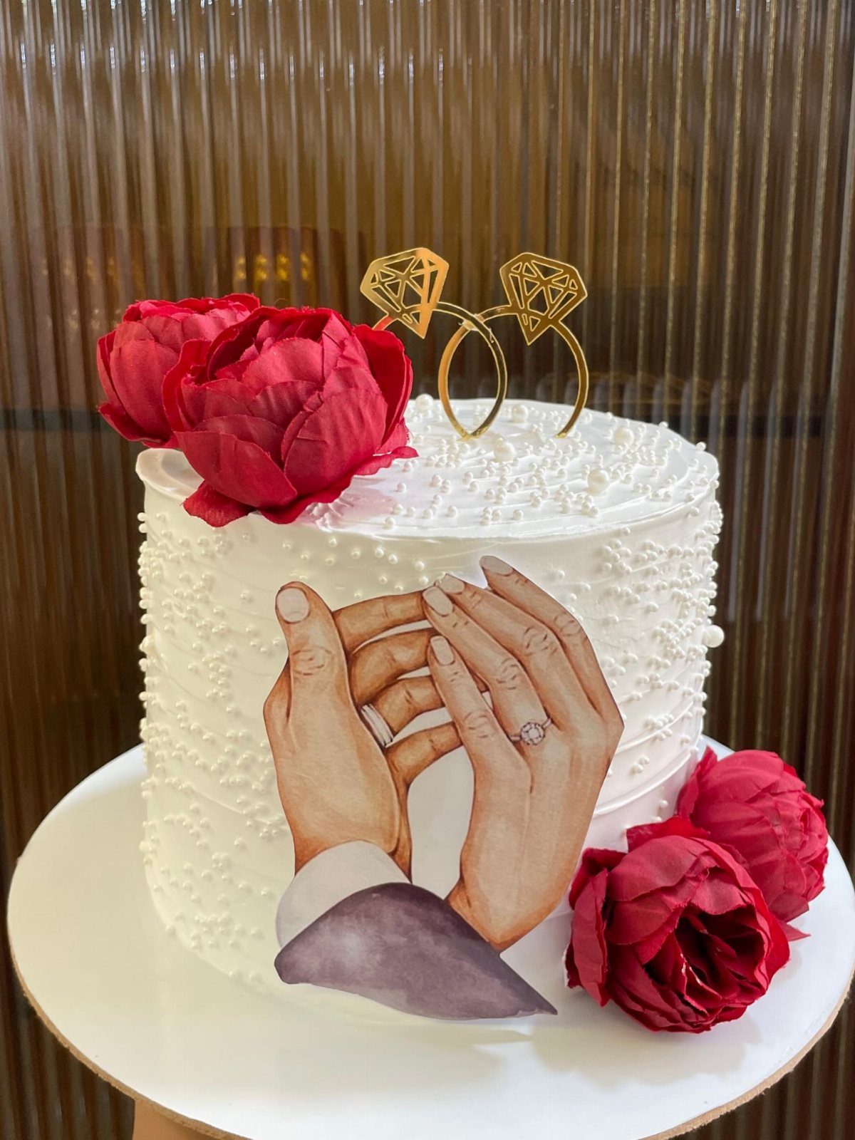 White pearl cake with red roses and an edible photo of holding hands.