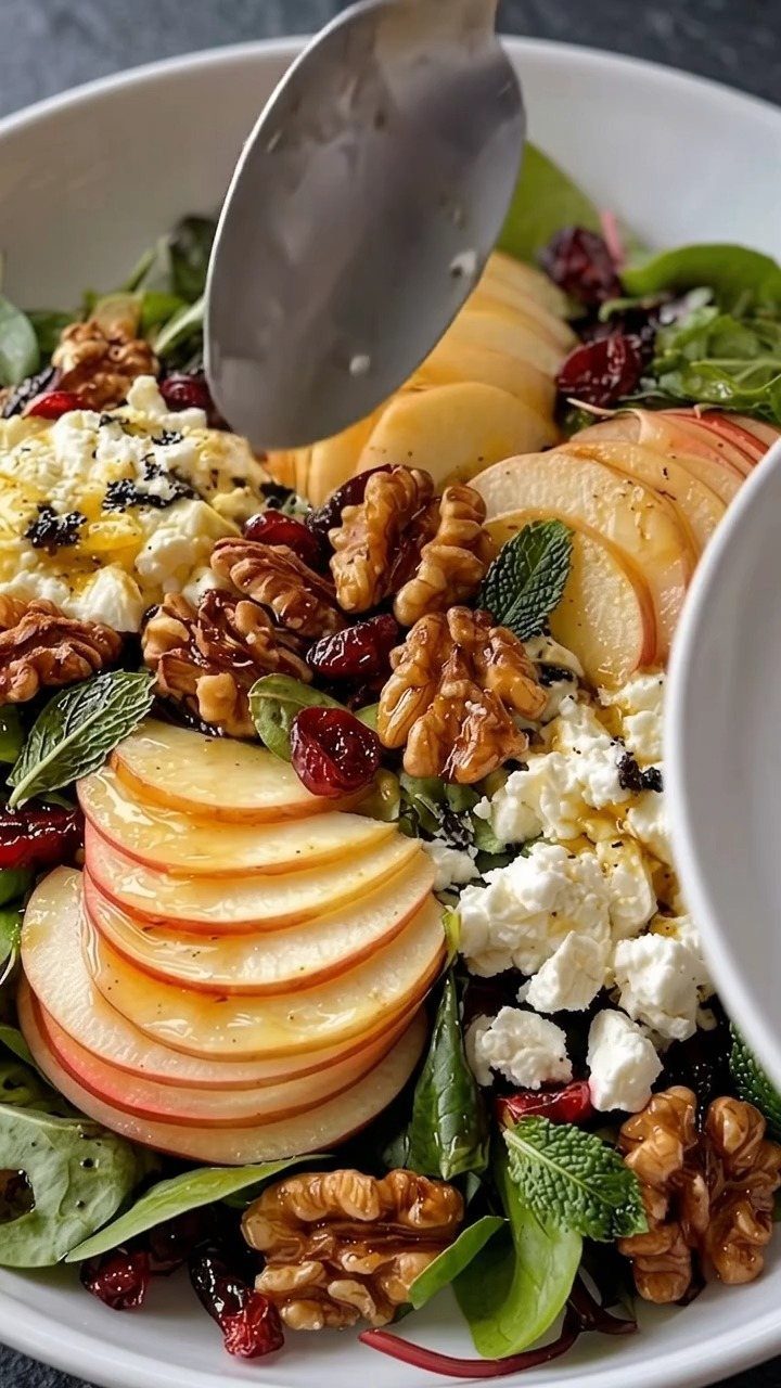 Apple walnut salad with feta cheese and cranberries in a white bowl.