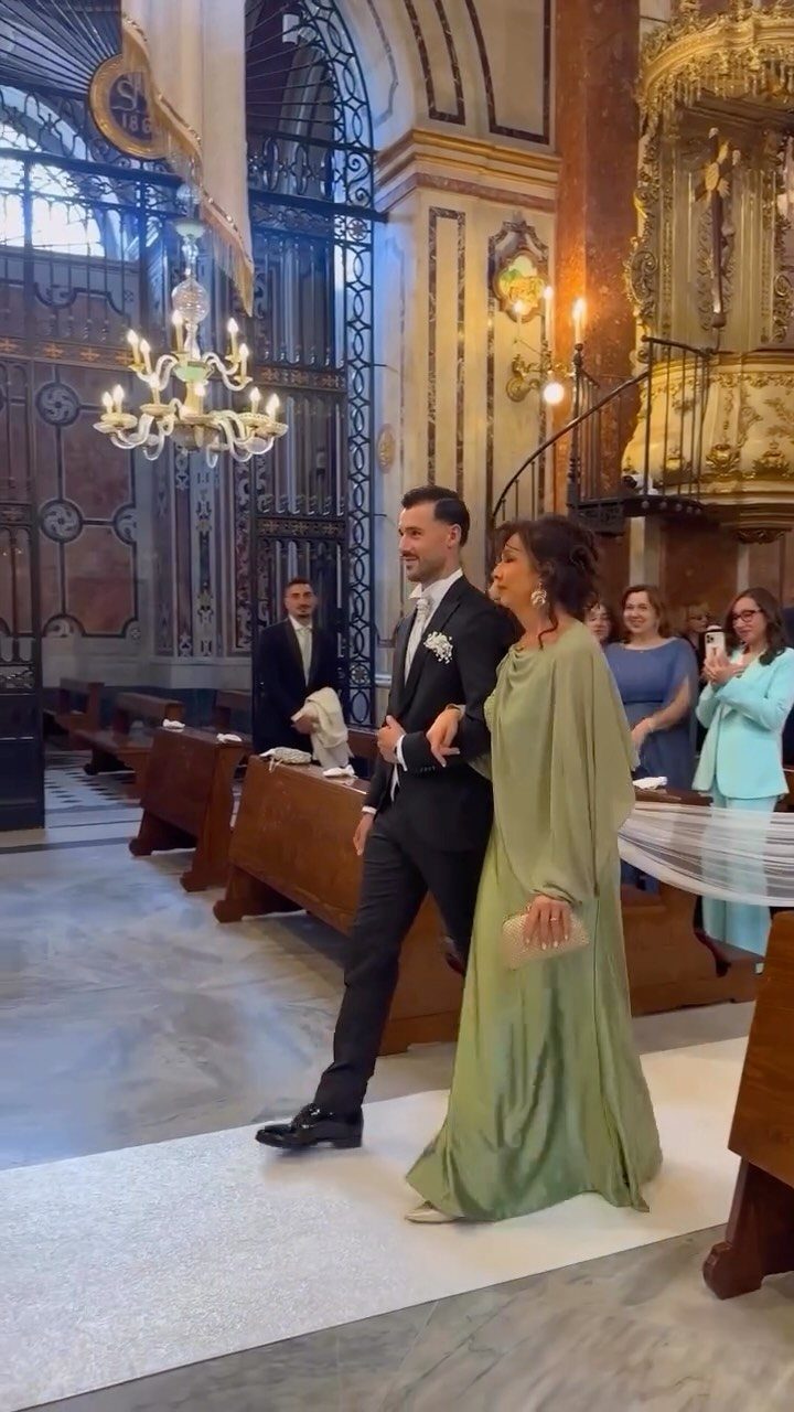 Groom and woman in green dress walking down church aisle during wedding