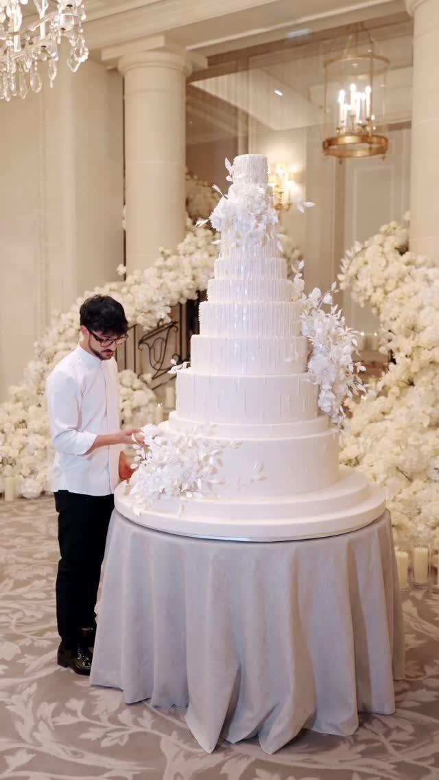 Multi-tiered white wedding cake with white flowers placed between the tiers.