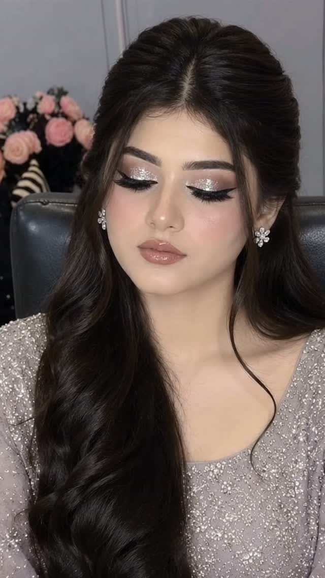Woman with silver glitter eyeshadow and nude lipstick wearing a shimmering silver dress