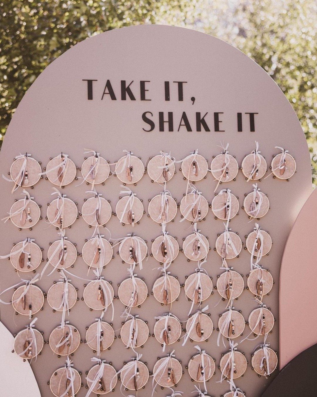 Pink arched wedding sign with shakers and text saying Take It Shake It