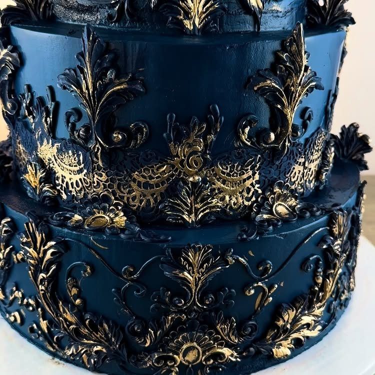 Navy blue tiered cake with ornate gold gilded baroque filigree decorations.