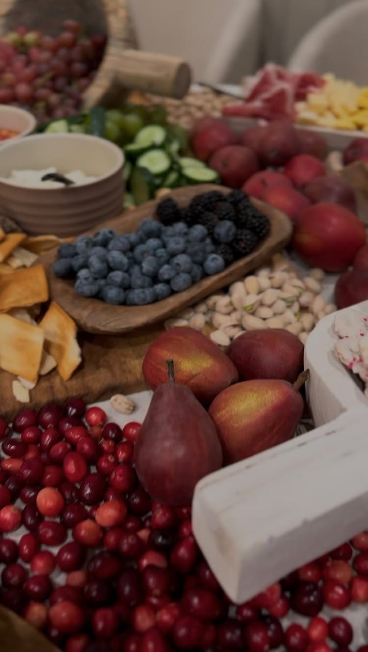 Assorted fruits, nuts, and dips arranged in wooden trays and bowls on a table.