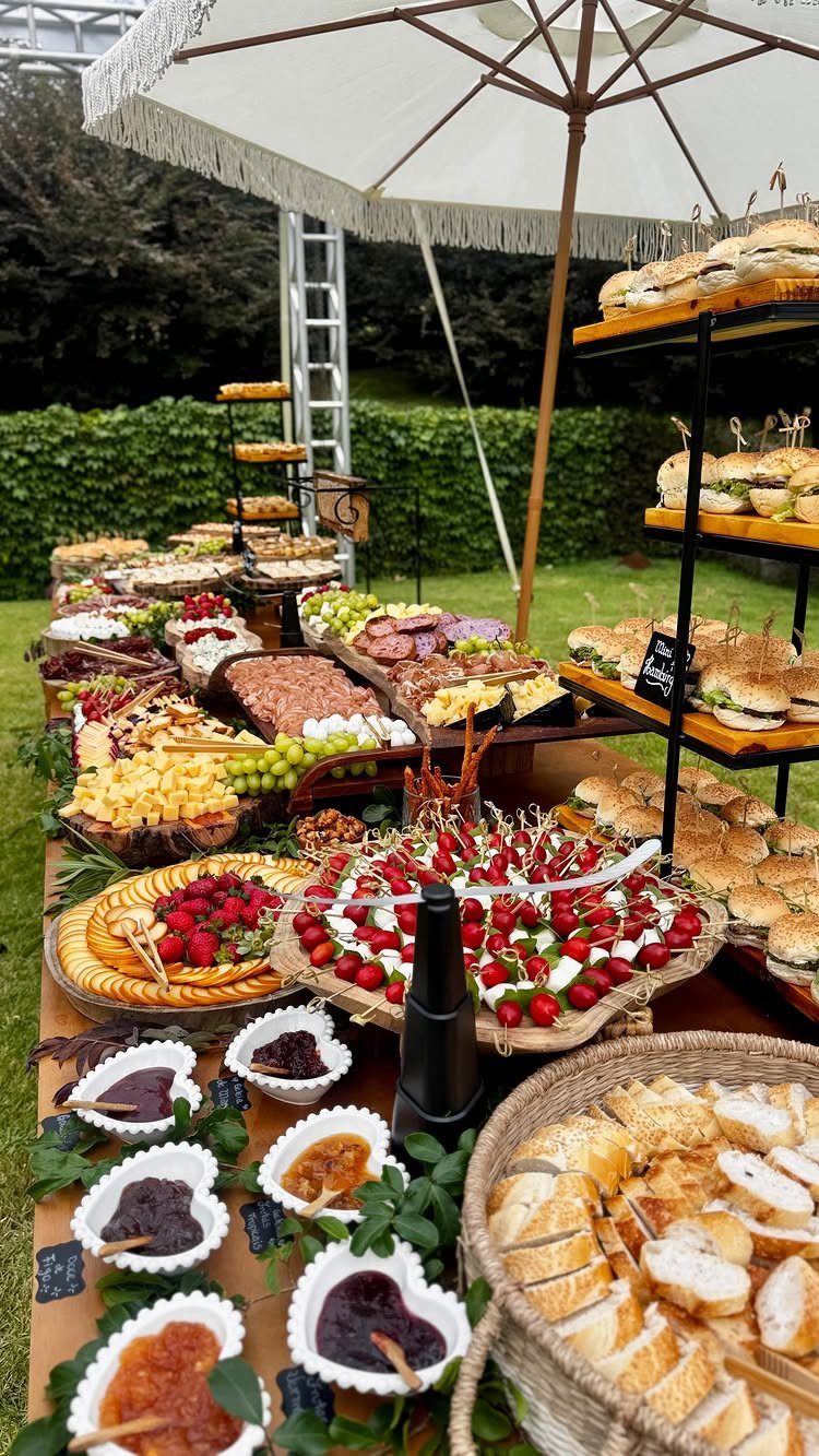Outdoor grazing table with fresh strawberries, grapes, cured meats, and sliced bread.