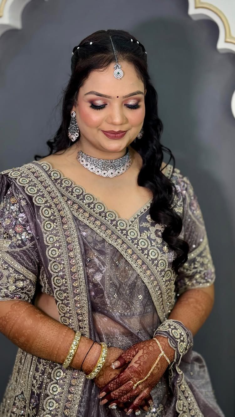 Woman in grey bridal attire with long curly hair swept to one side.
