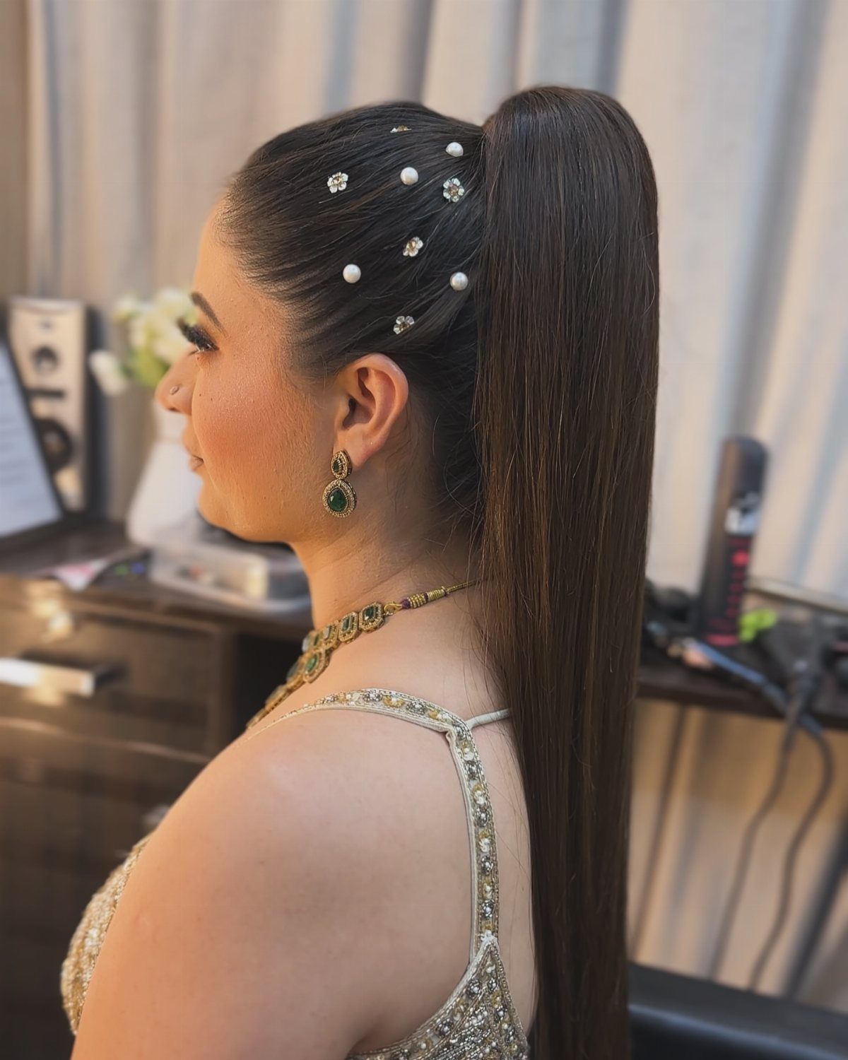 Woman with a high sleek ponytail adorned with white pearl hair pins.