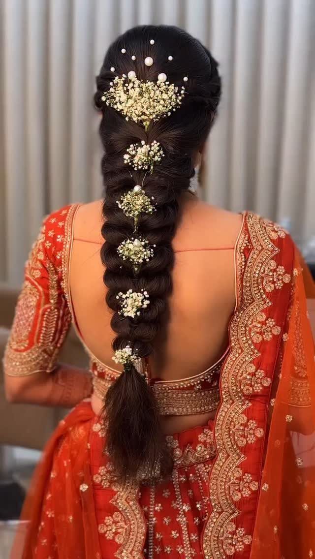 Long dark braid adorned with white flowers and pearls on an Indian bride.