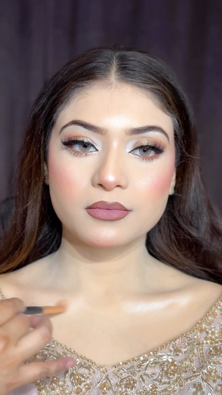 Woman receiving bridal makeup application on her collarbone with a makeup brush