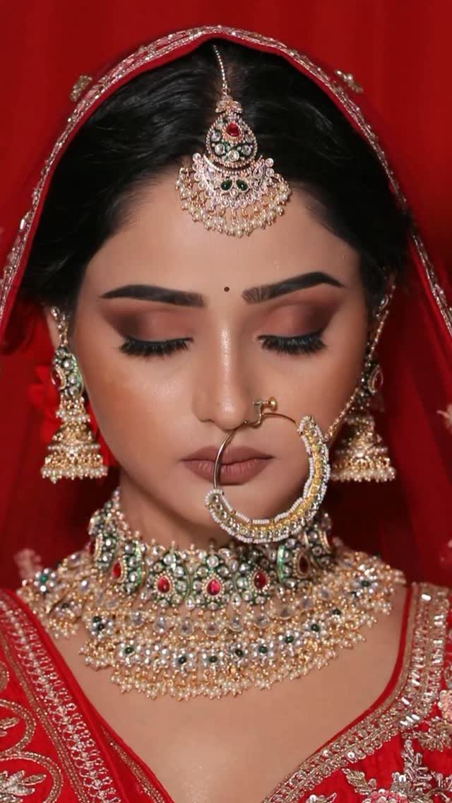Indian bride with bronze smokey eyes wearing heavy gold jewelry and red veil