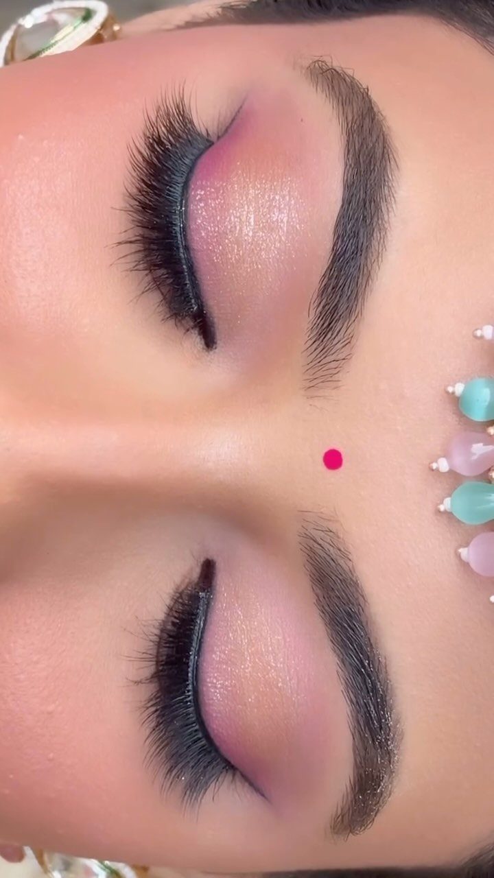 Closed eyes with long false lashes, pink eyeshadow, and a red bindi.