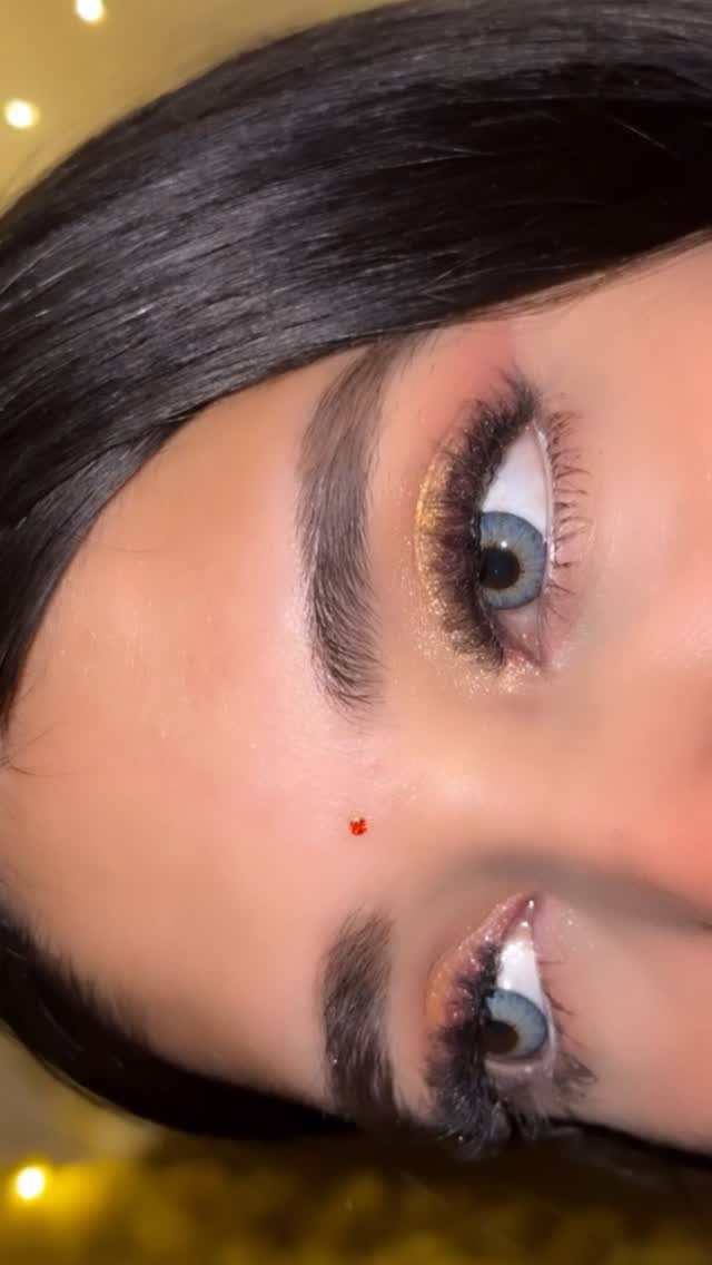 Close-up of eyes with gold shimmer eyeshadow and a small red bindi.