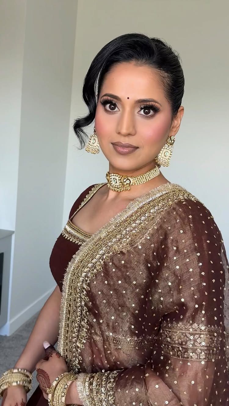 Woman with matte brown eyeshadow wearing a brown embroidered saree and gold jewelry