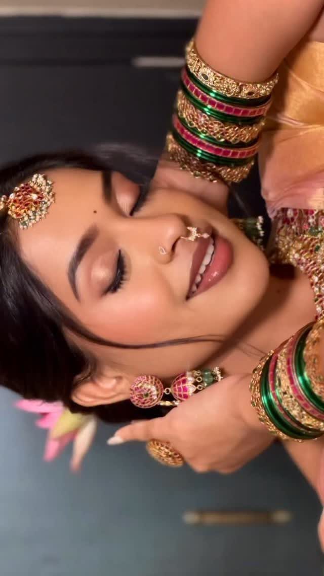 Indian bride with nude lips, gold jewelry, and green and gold bangles.