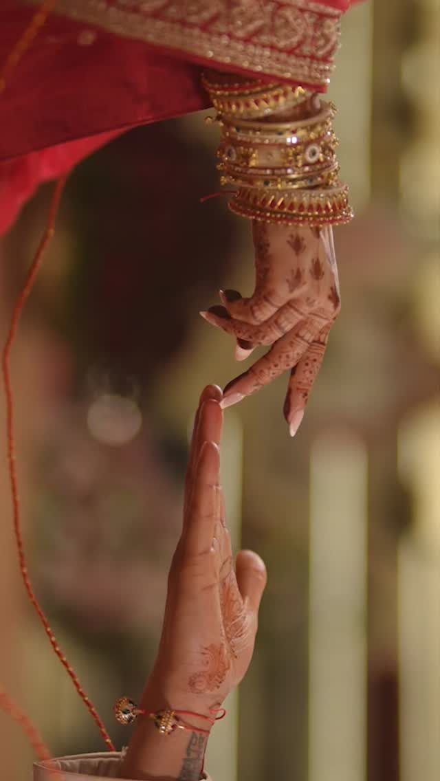 Henna decorated hands of a couple touching fingers during an Indian wedding ceremony.