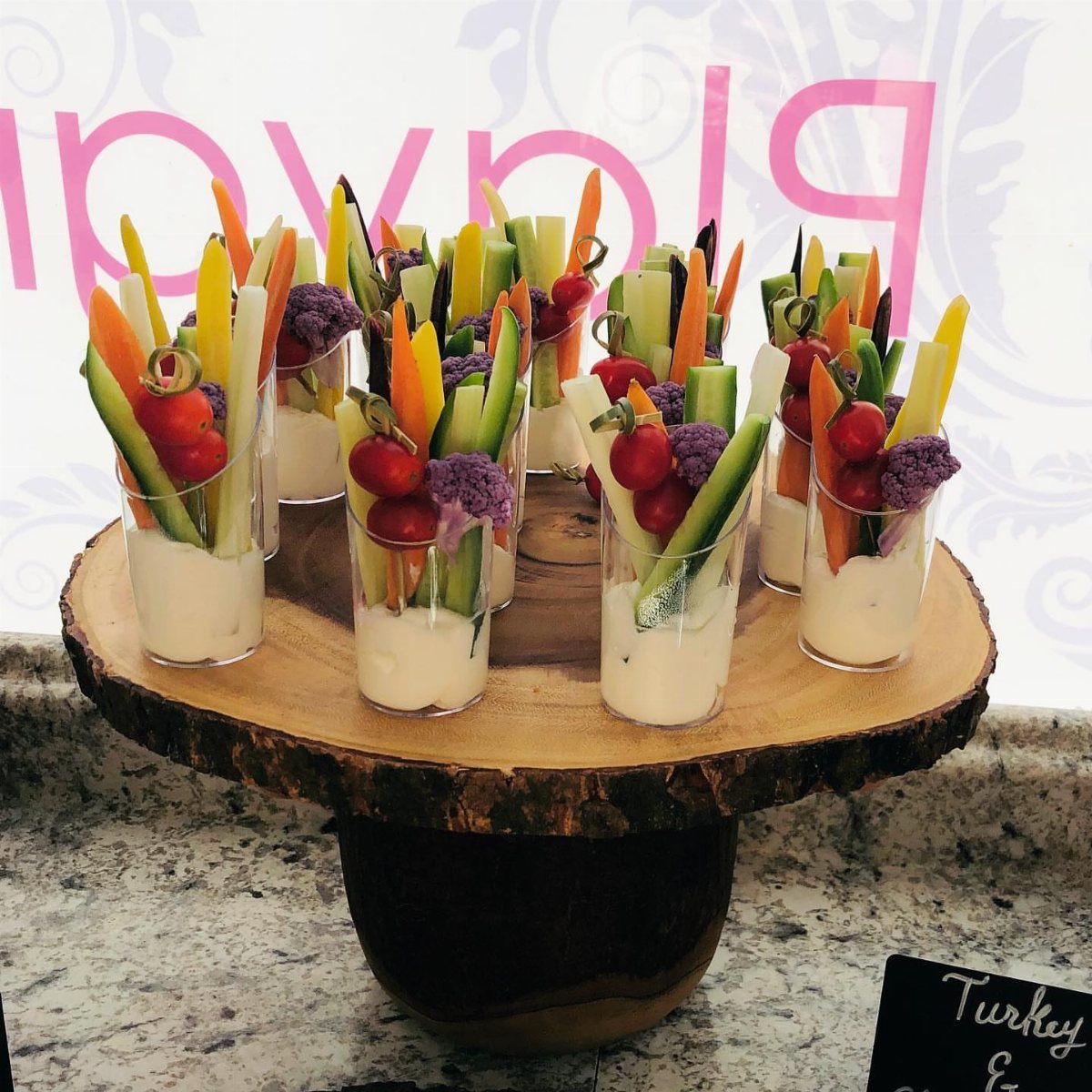 Vegetable sticks in small cups with white dip on a wooden platter