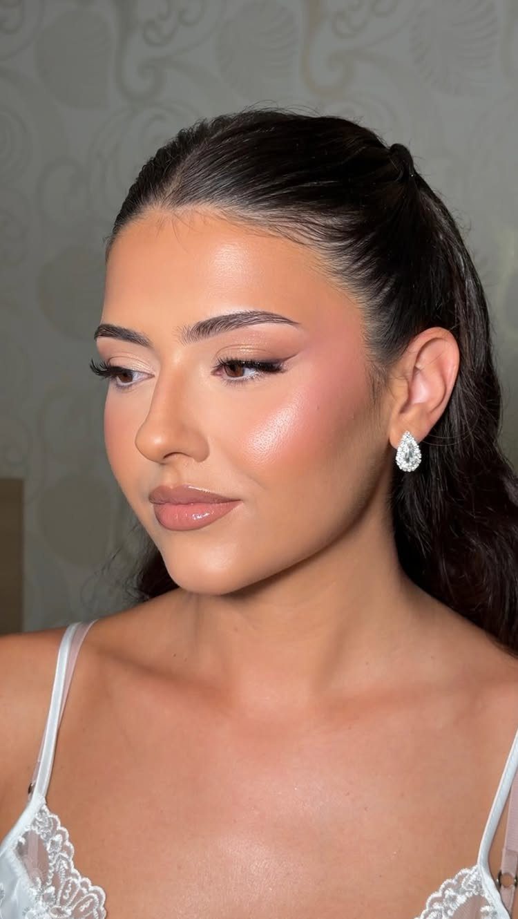 Woman with glowing natural wedding makeup, nude lips, and white lace dress.