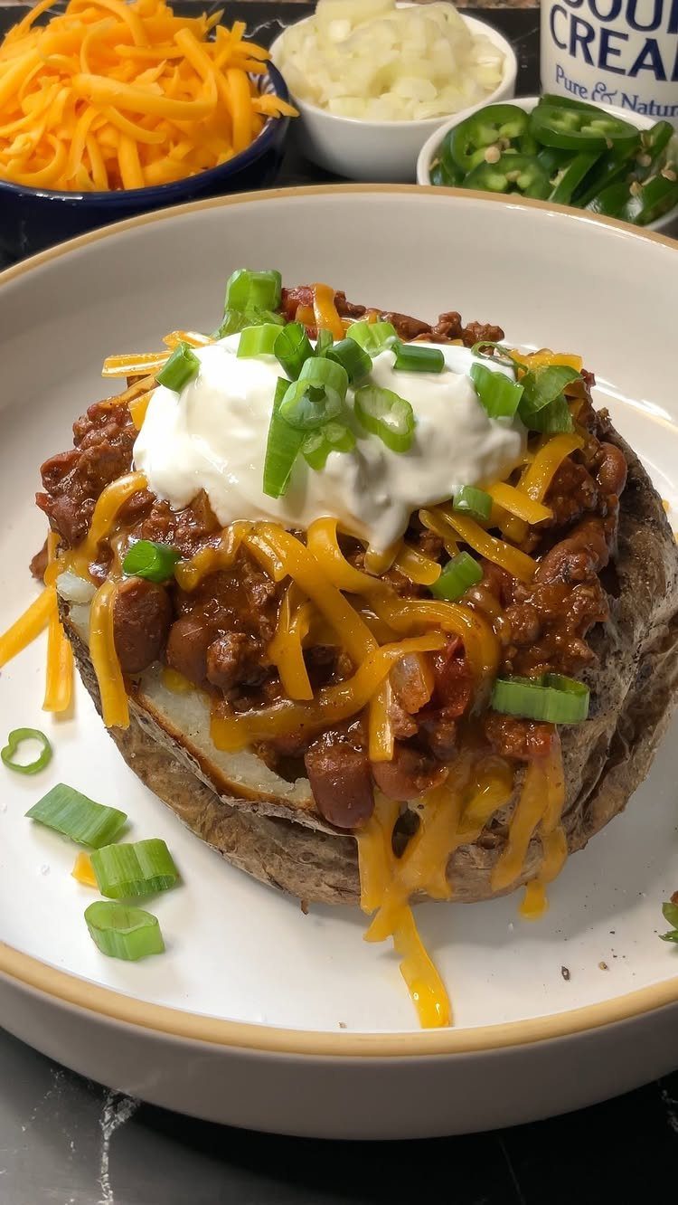 Loaded baked potato topped with chili, cheese, sour cream, and green onions.