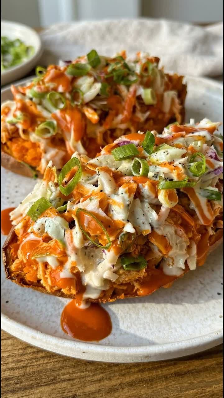 Stuffed sweet potatoes topped with buffalo chicken, white sauce, and green onions.