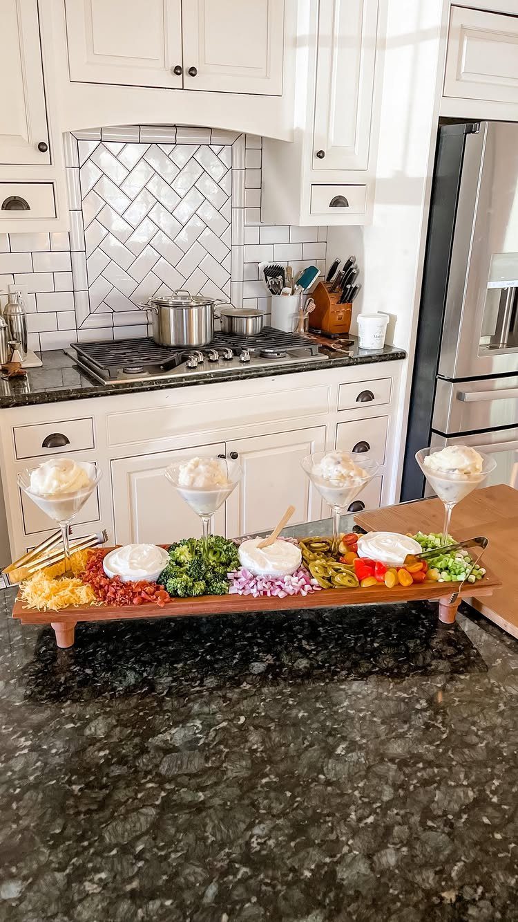 Mashed potatoes in martini glasses on a wooden platter with colorful toppings.
