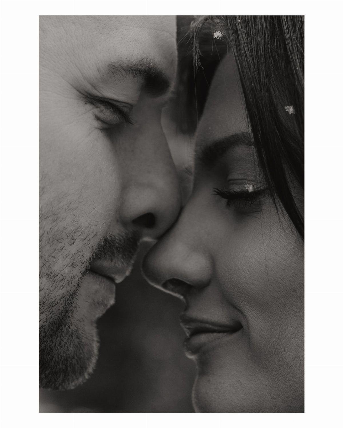 Couple in a black and white close-up, touching foreheads with eyes closed.