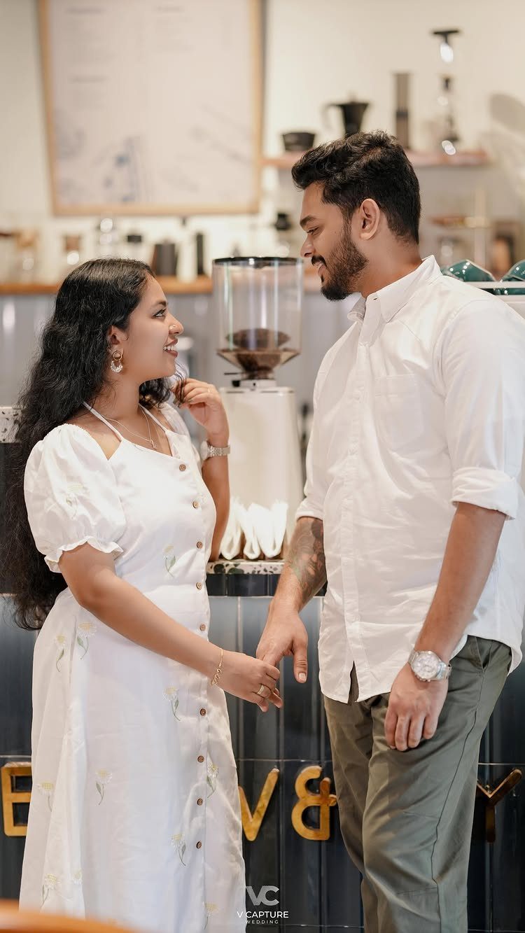 Couple holding hands and gazing at each other inside a modern coffee shop.