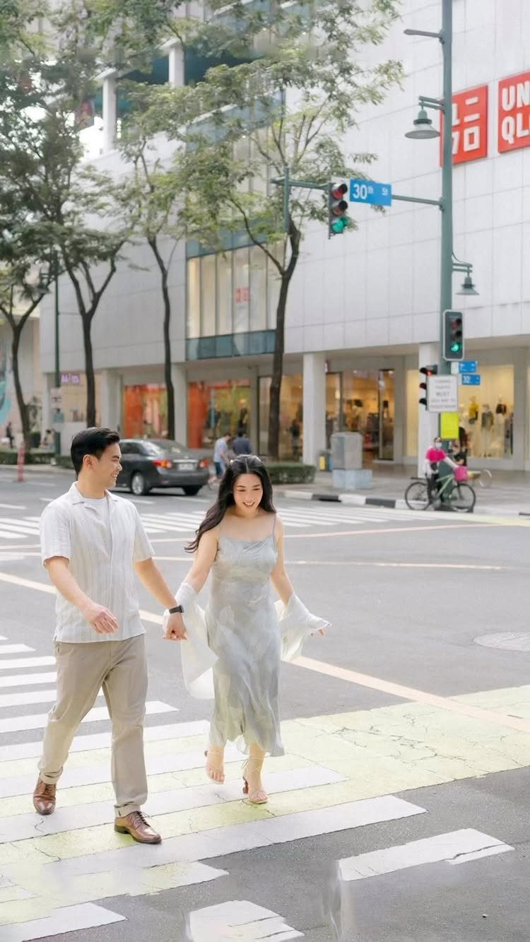 Couple holding hands while walking across a city street in formal attire.