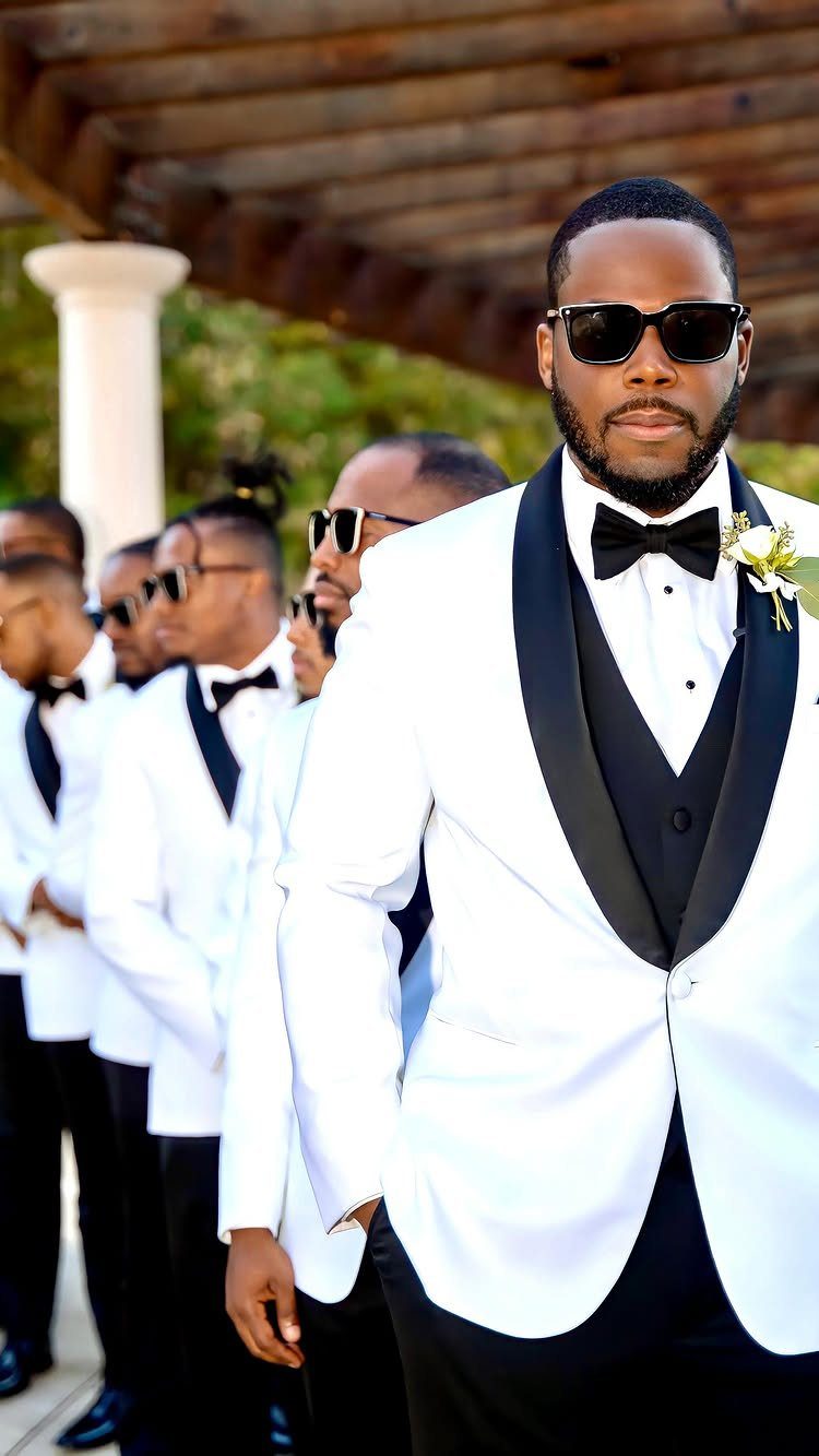 Groom and groomsmen wearing white tuxedo jackets and black sunglasses outdoors