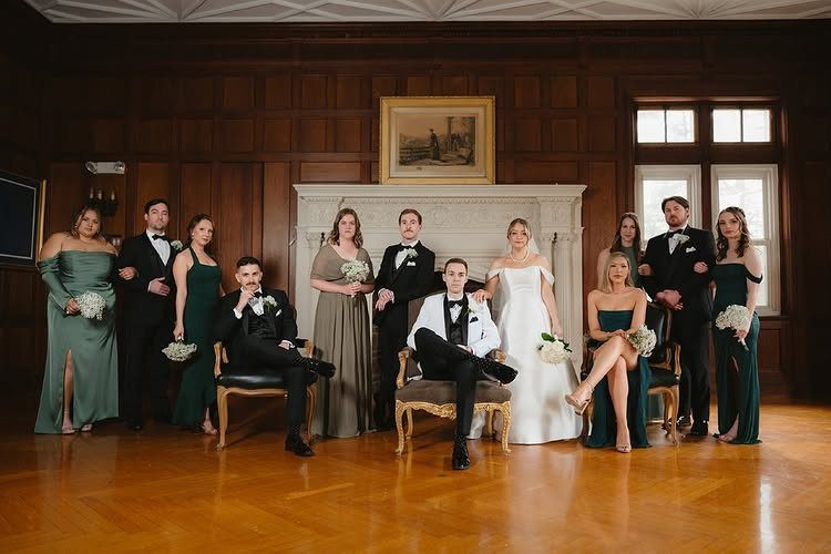Wedding party posing in a wood-paneled room with a bride and groom centered.