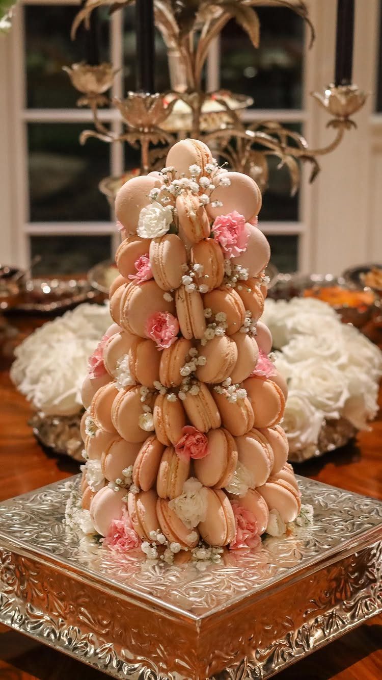 Macaron tower decorated with pearls and flowers on an ornate silver platter.