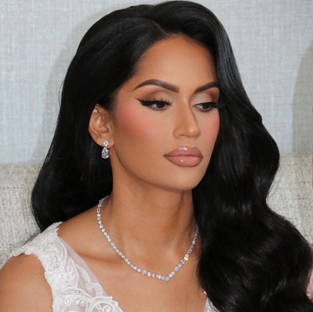 Woman with glamorous wedding makeup featuring a glossy beige-pink pout and winged eyeliner