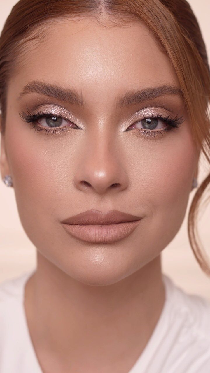 Woman with shimmering champagne eye makeup and matte nude lips posing for portrait