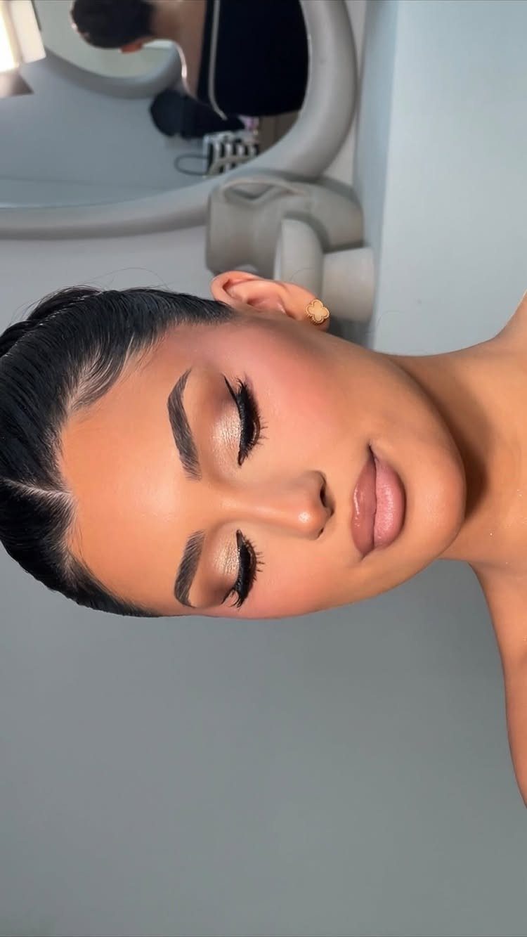 Woman with bronzy neutral latte makeup, long lashes, and nude glossy lips.