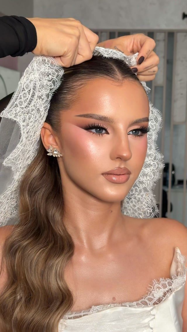 Woman with glam wedding makeup wearing a white lace veil and dress