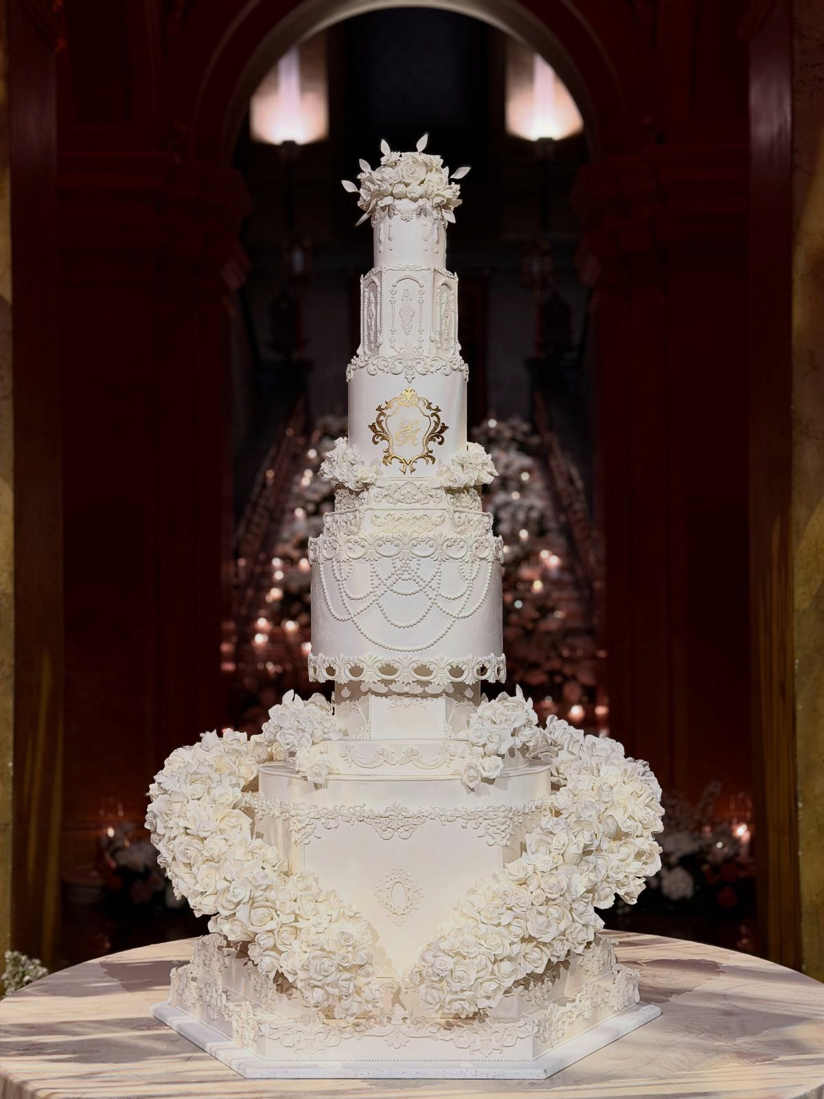 Tall white multi-tiered wedding cake with intricate frosting and floral decorations.