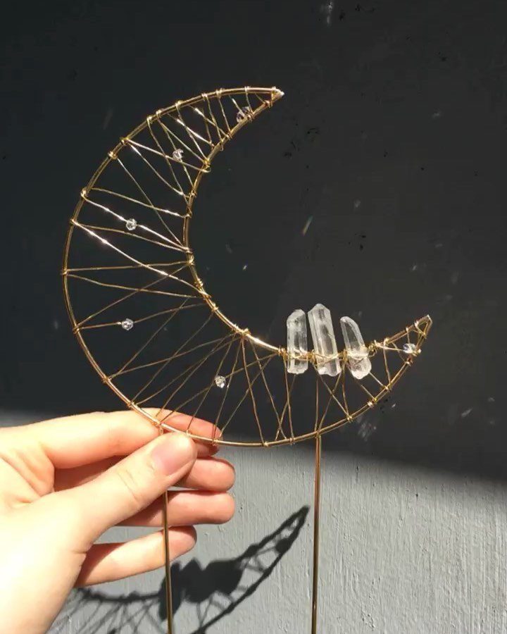Gold wire crescent moon cake topper with clear quartz crystals held by a hand