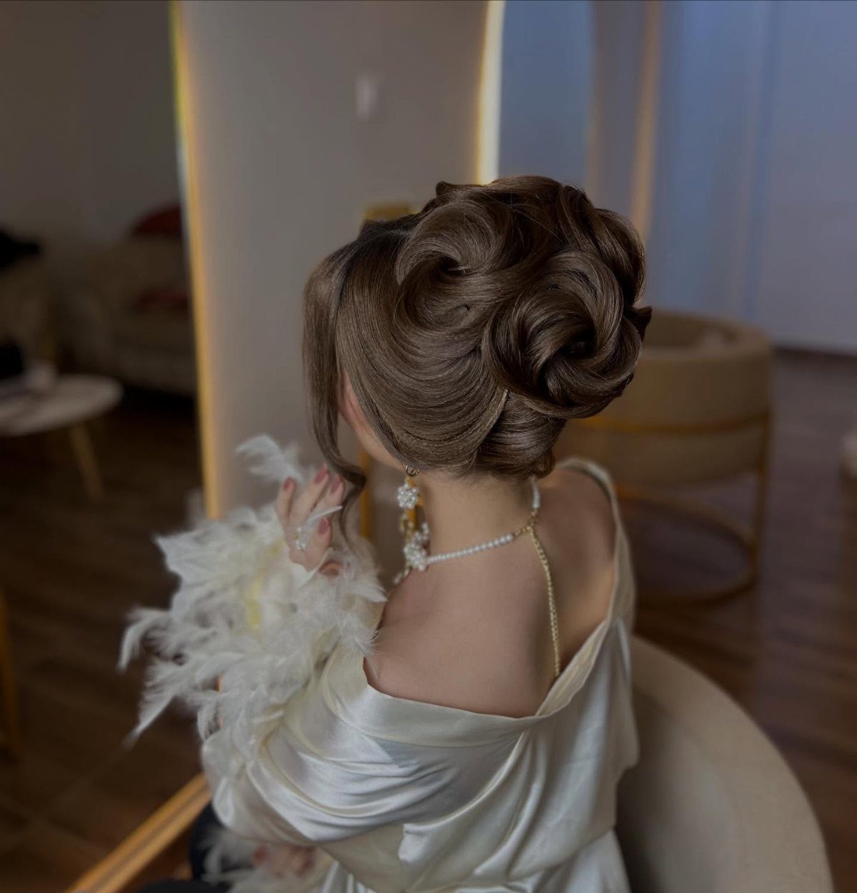 Woman with a voluminous brown bouffant updo wearing a white satin robe