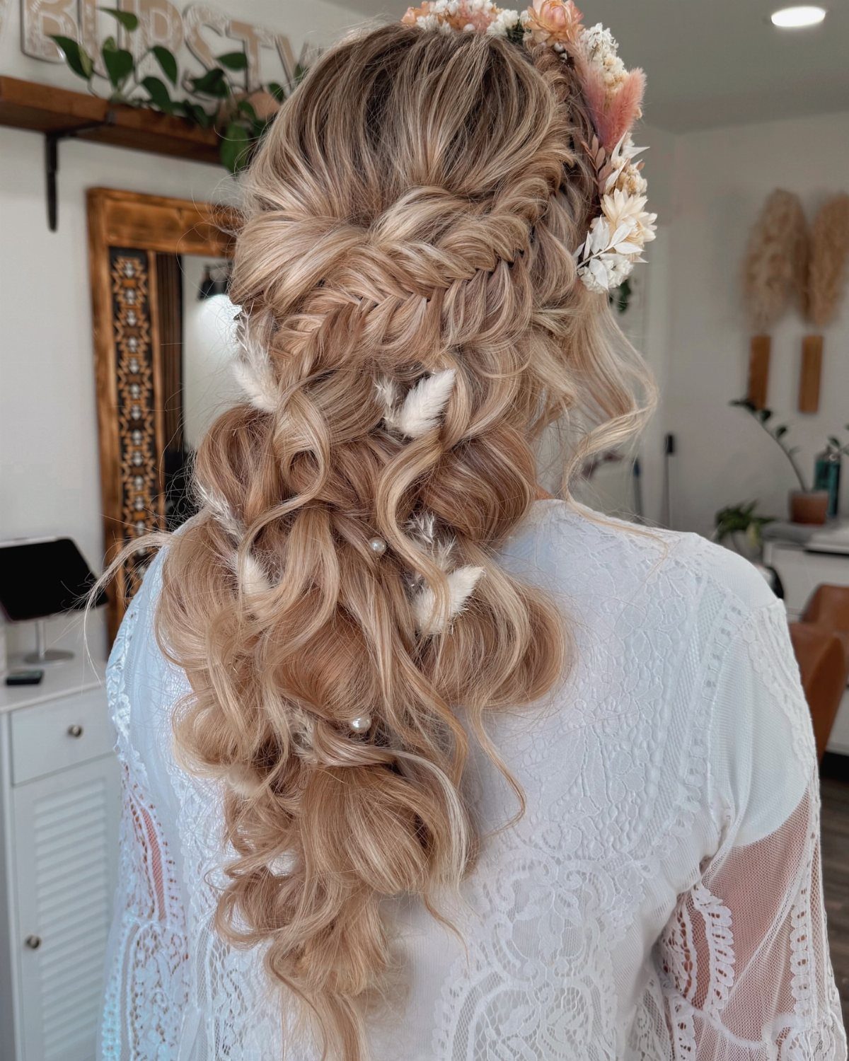 Blonde curly hair in a half-updo adorned with a crown of large flowers