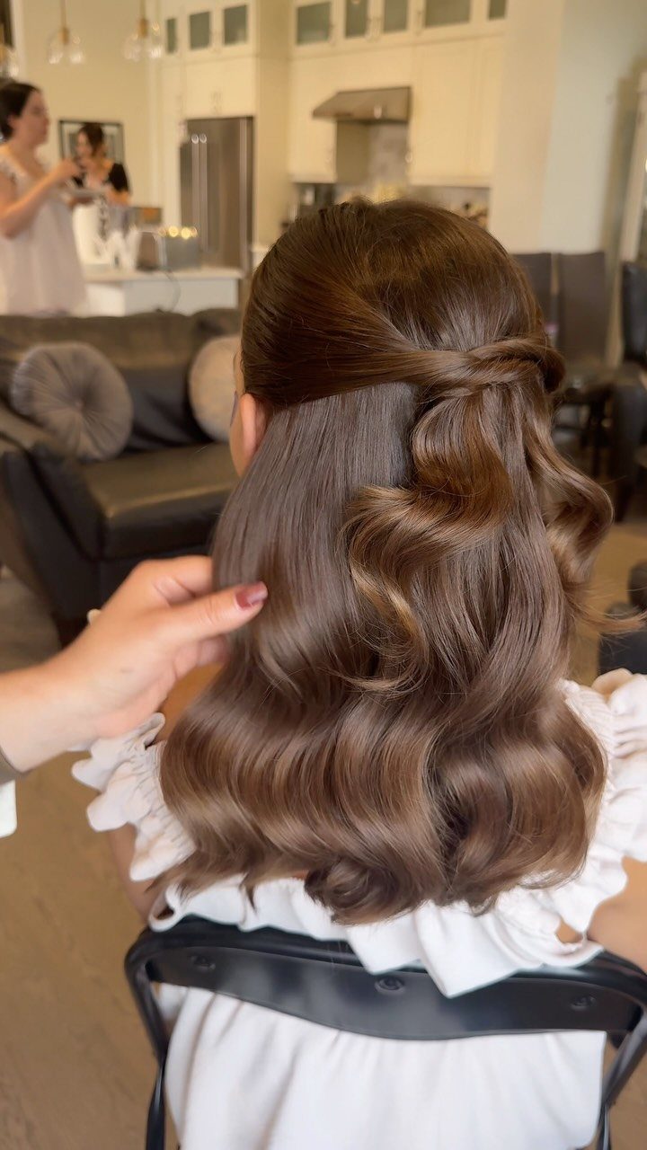 Brown hair styled in a half-up half-down look with voluminous curls and waves.