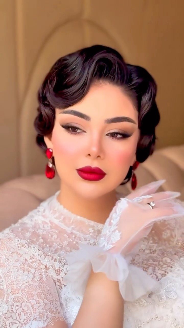 Woman with polished Old Hollywood waves, red lips, and white lace wedding attire.