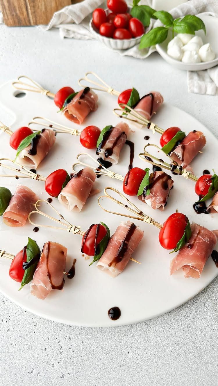 Prosciutto and cherry tomato skewers with balsamic glaze on a white platter