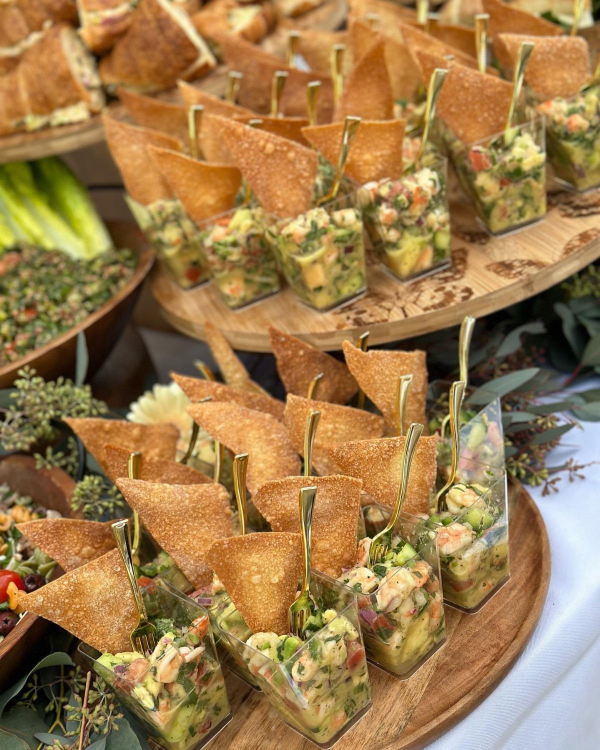 Ceviche shooters with shrimp and avocado topped with tortilla chips on wooden platters.