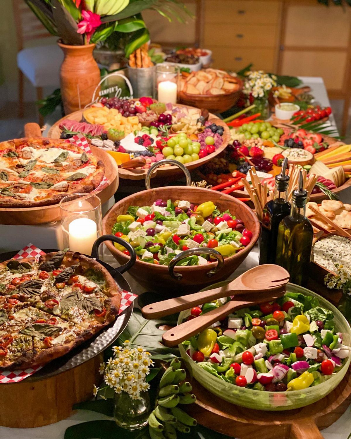 Grazing table with pizzas, Greek salads, cheese, and fruit platters for a wedding.