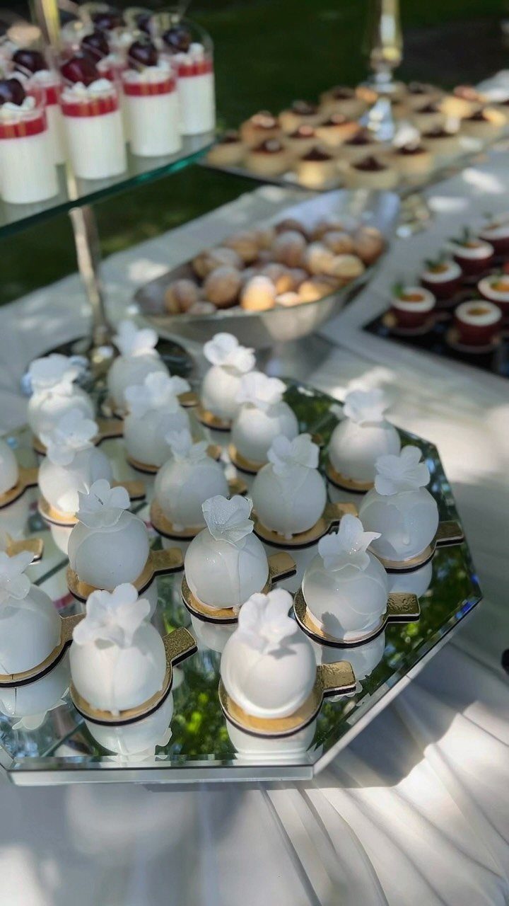 Miniature white cake pops and berry cream cakes on a wedding dessert station.