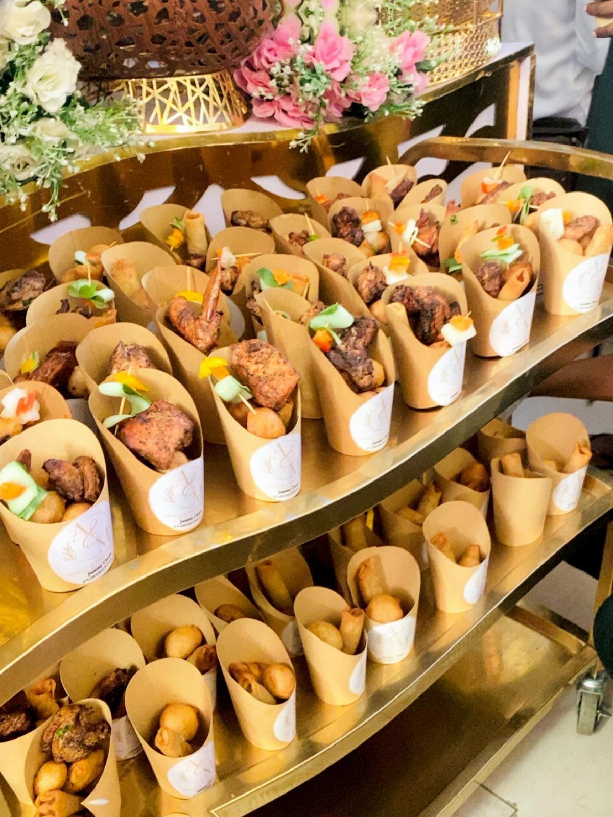 Appetizers in brown paper cones on a tiered gold buffet display stand.