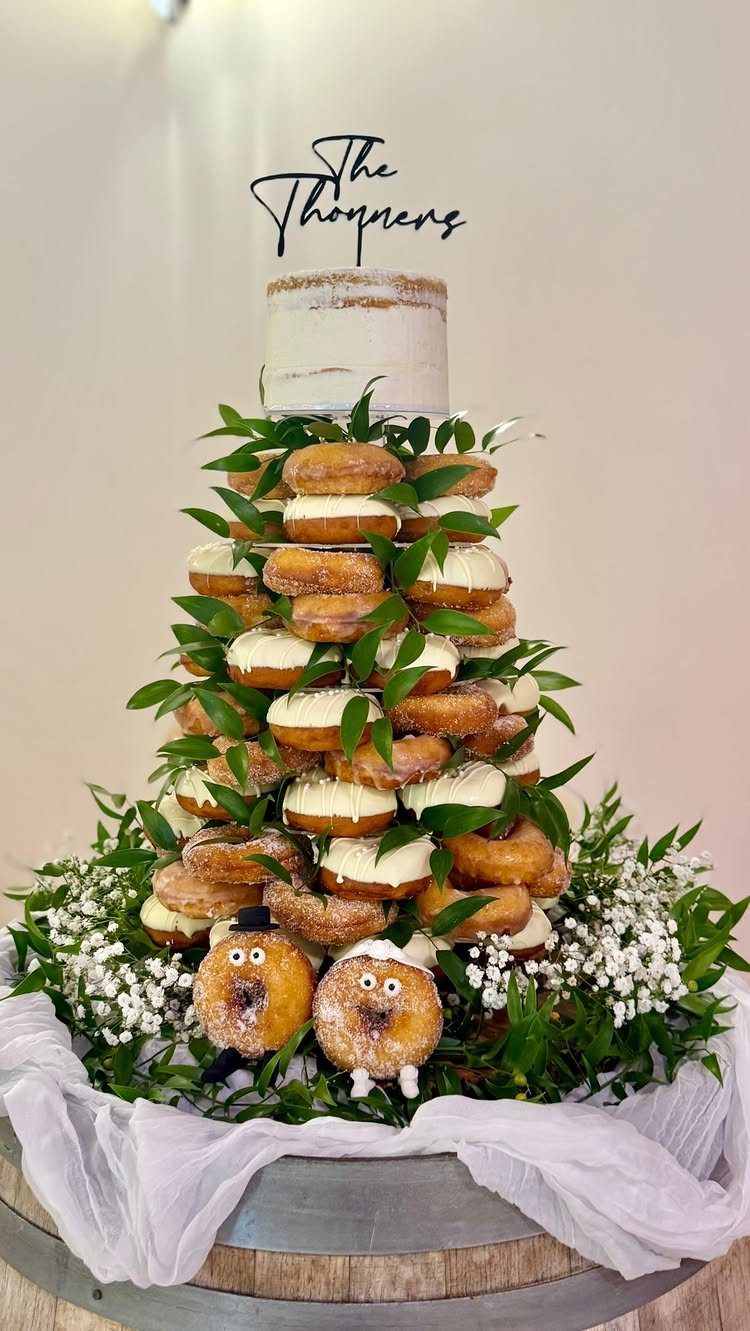 Doughnut tower wedding cake topped with a small cake and custom name topper.