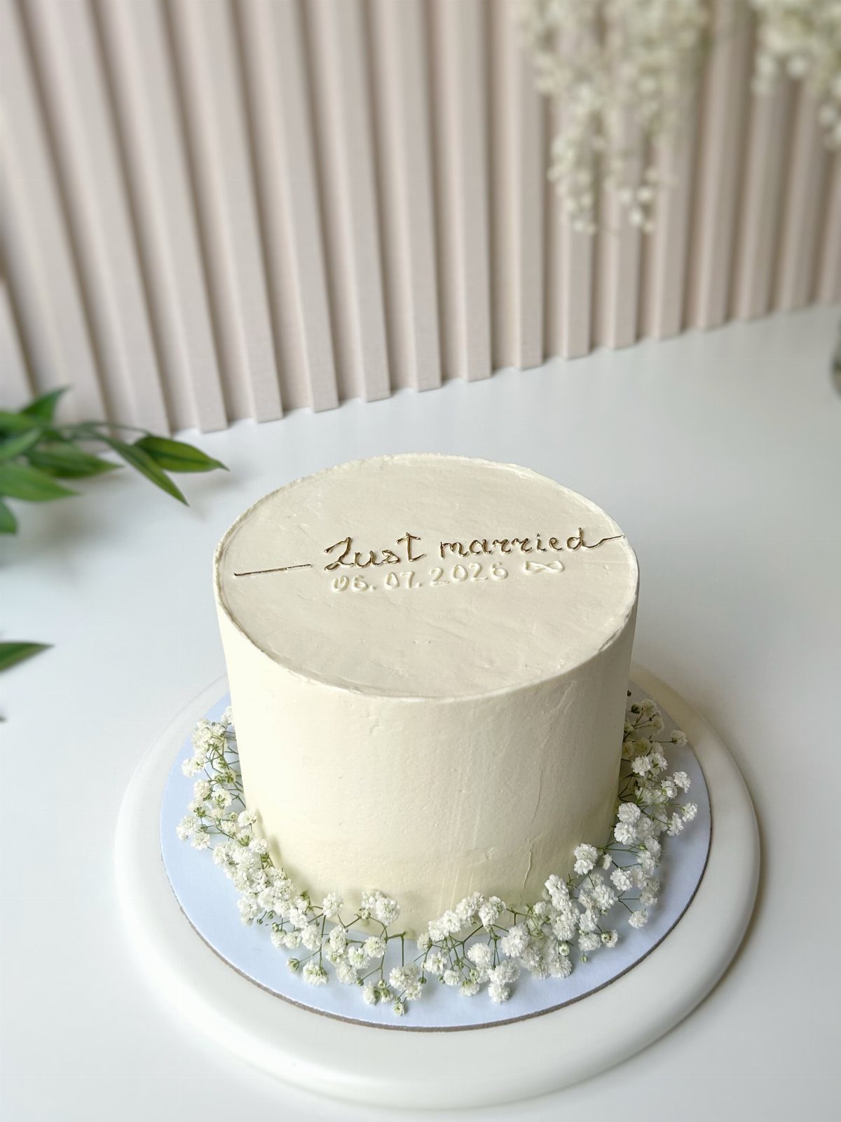 Single-tier white wedding cake with baby's breath flowers and just married inscription